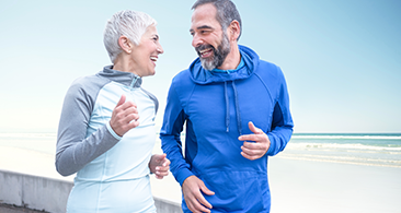 Older couple running outside in training gear